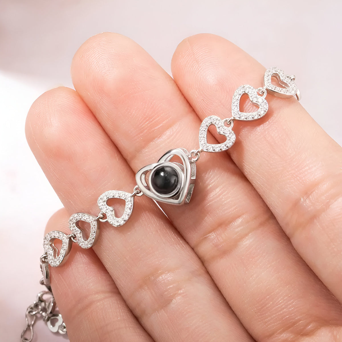 Bracelet en argent sterling à multiples cœurs, cœur central orné d'une pierre noire brillante.