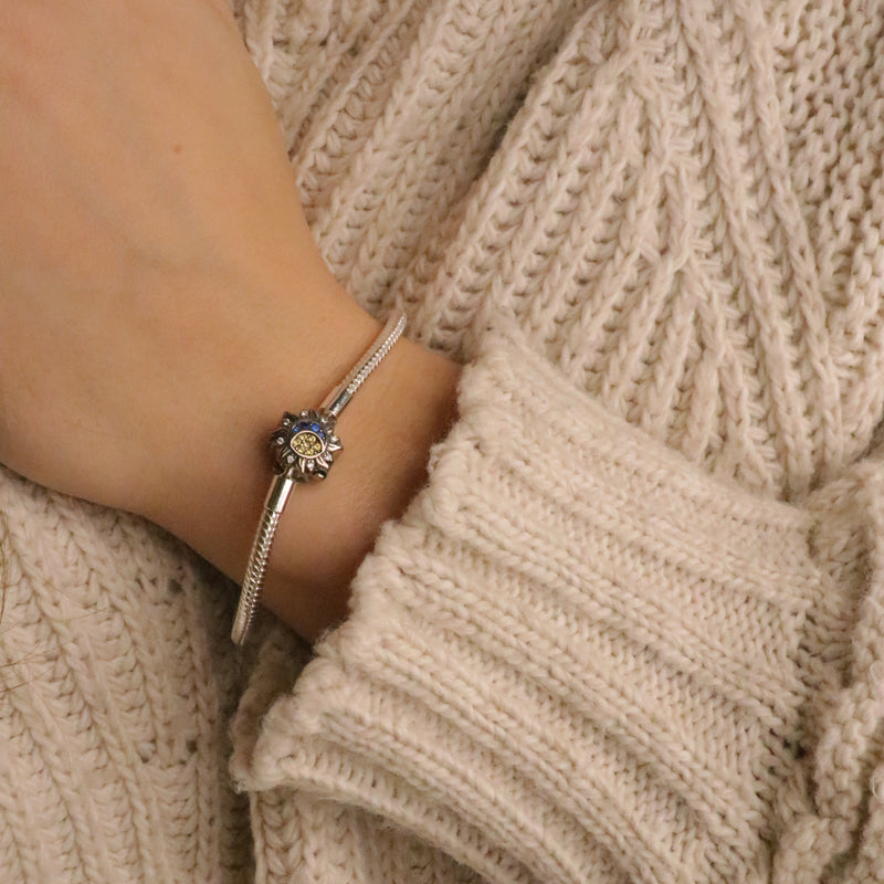 Bracelet argenté fin avec pendentif soleil et lune orné de petits cristaux scintillants, porté au poignet féminin.