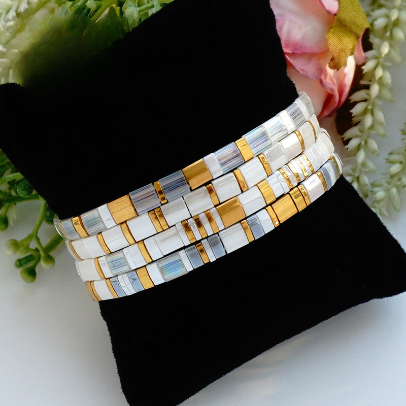 Ensemble de quatre bracelets élastiques en perles du Japon Tila, blanc lumineux, reflets irisés et détails dorés, modèle Atzuki