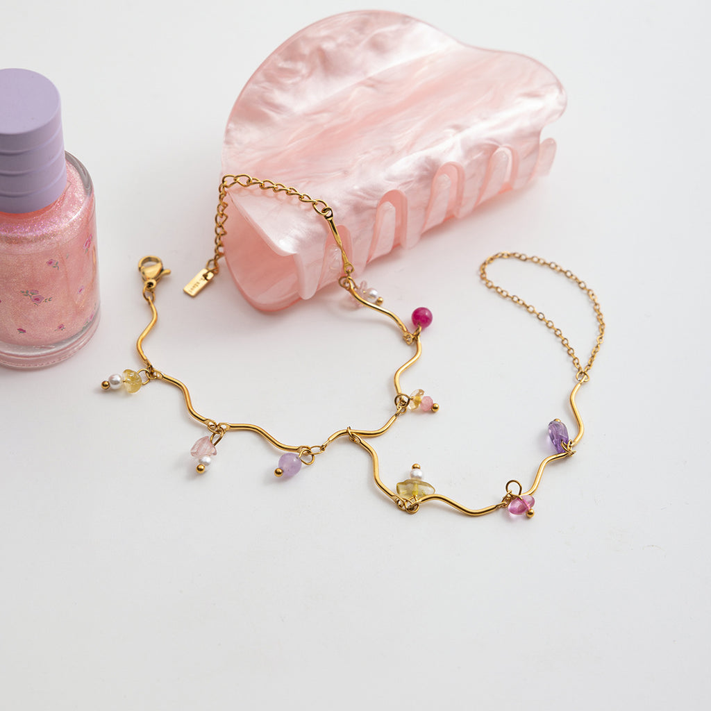 Bracelet de main doré en acier inoxydable avec chaînes fines et pierres naturelles colorées multiformes.