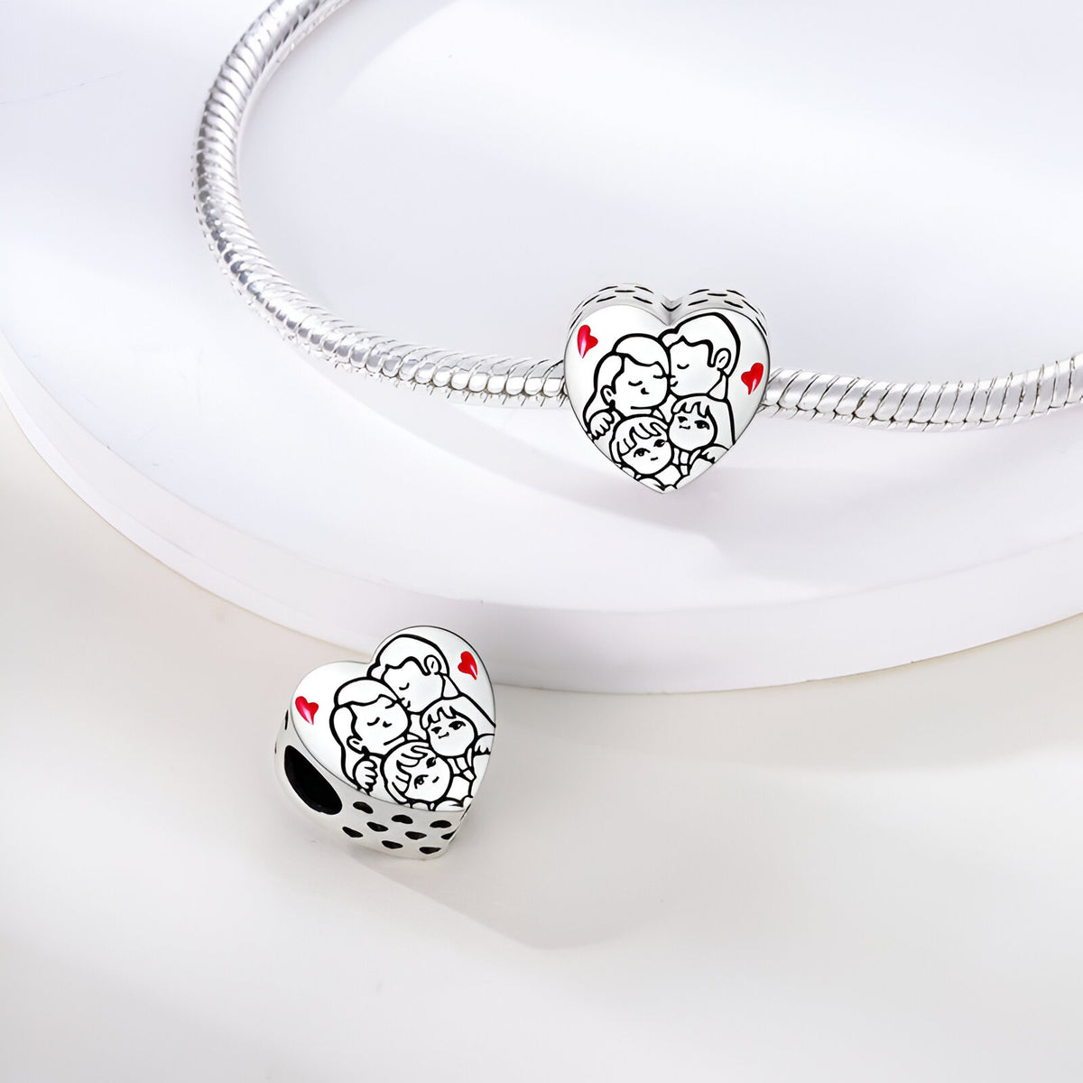 Charm en forme de cœur en argent avec gravure famille et petits cœurs rouges.