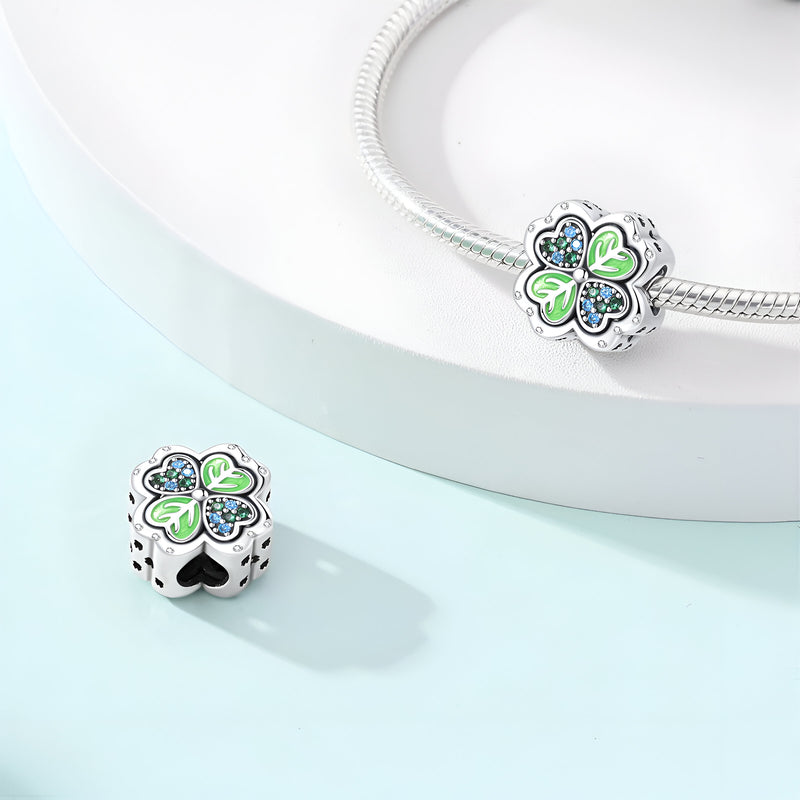 Charm trèfle à 4 feuilles argenté avec détails verts et bleus, design délicat et élégant.