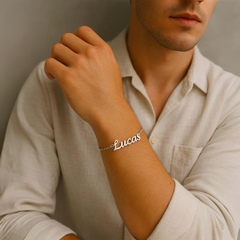 Bracelet prénom personnalisé en acier inoxydable argenté avec lettres script sur poignet masculin, style ajustable.