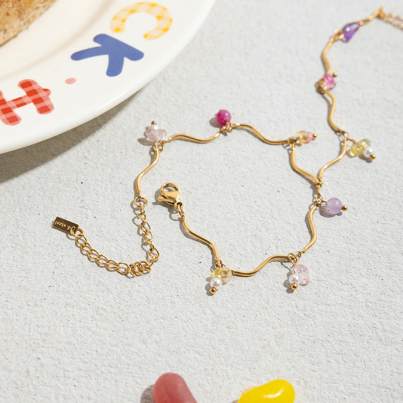 Bijou de main doré en acier inoxydable avec chaînette fine et pierres naturelles colorées en pendentifs délicats.