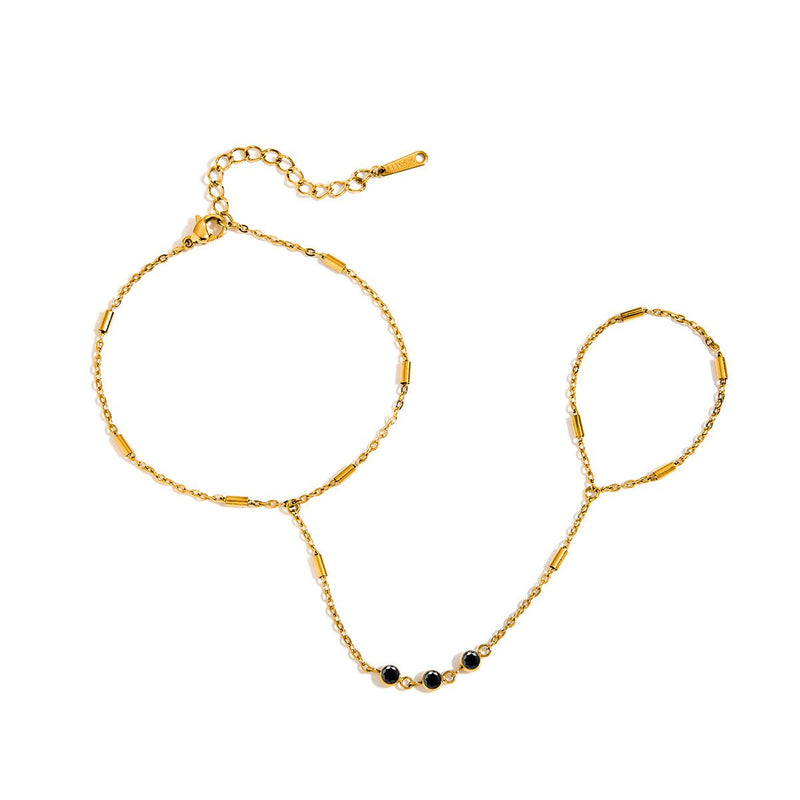 Bijou de main doré en acier avec chaîne fine, trois petits zircons noirs et anneau ajustable style bohème.