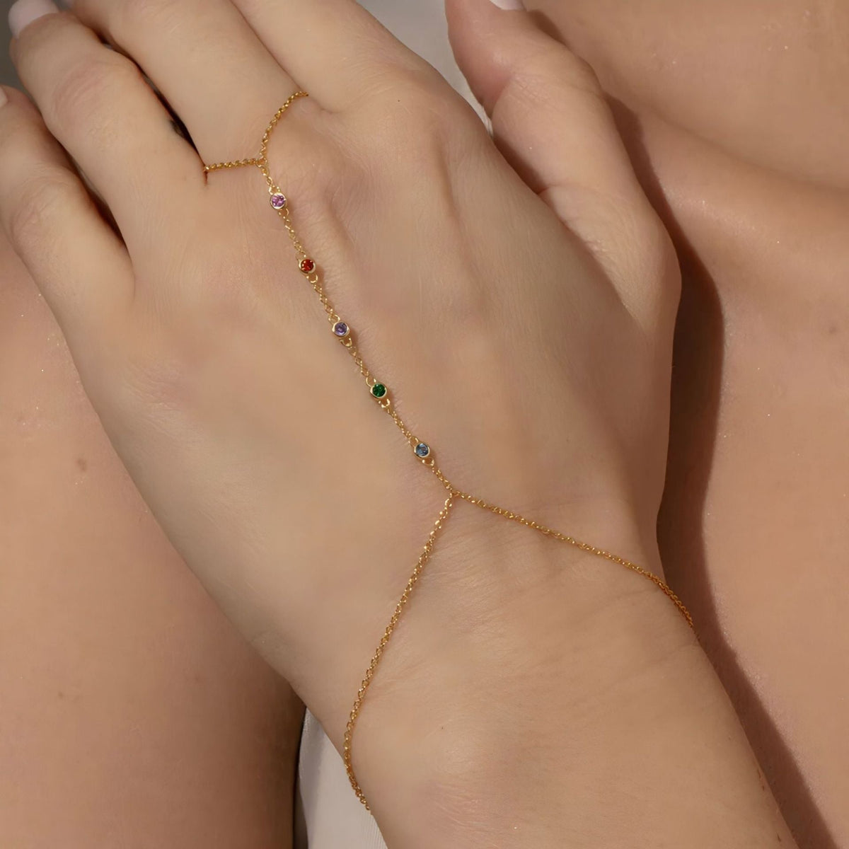 Bijou de main doré fin avec pierres de zirconium multicolores brillantes, style délicat et élégant.