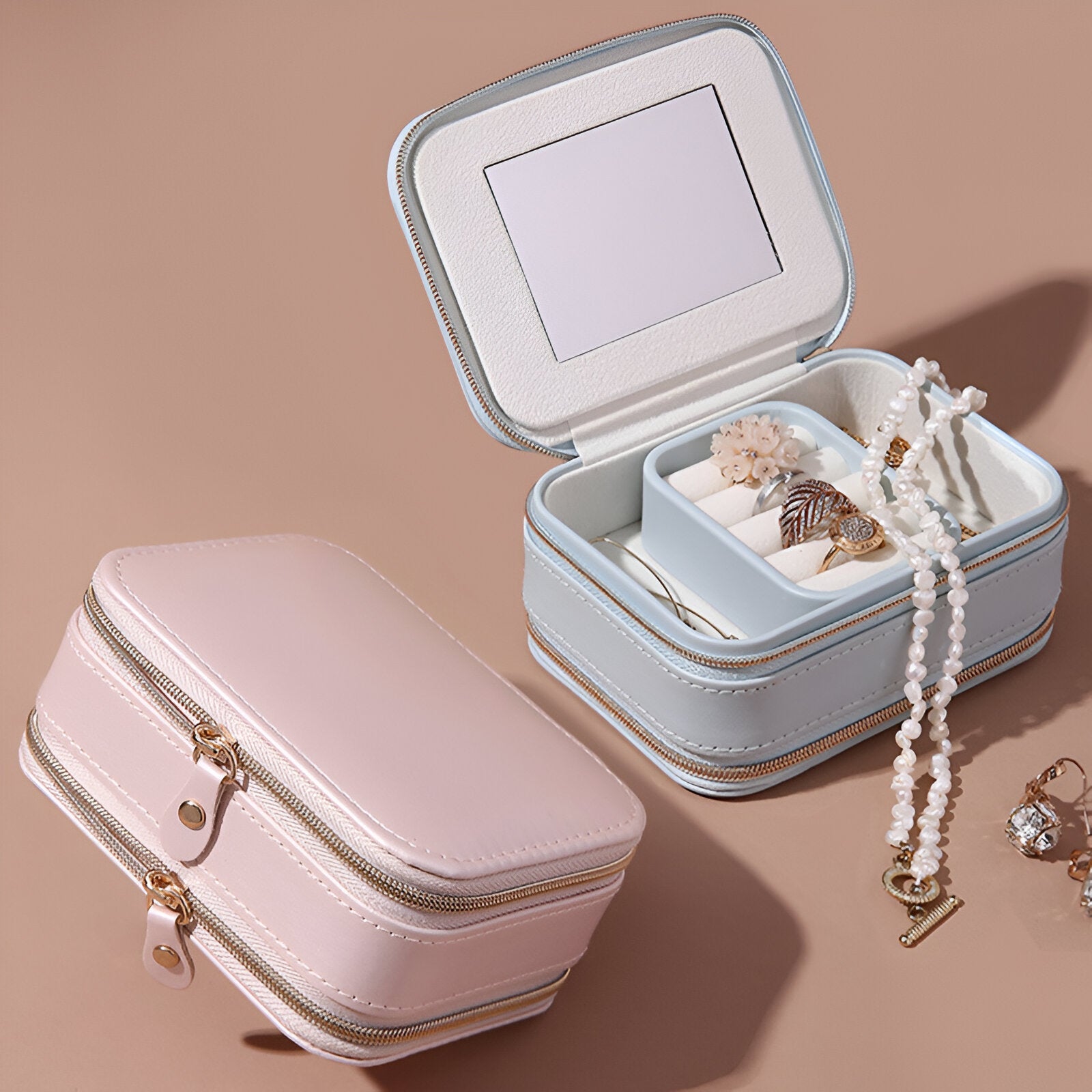Boîte à bijoux nomade rose en cuir avec double fermeture éclair, modèle Rocio, intérieur bleu avec miroir et compartiments.