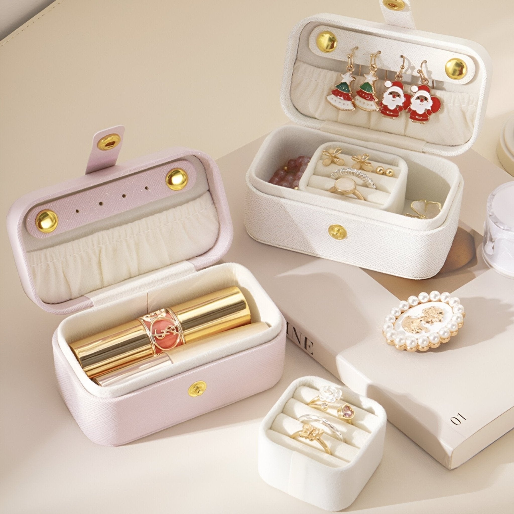 Boîte à bijoux nomade rose clair à compartiments, fermeture bouton doré et intérieur velours blanc.