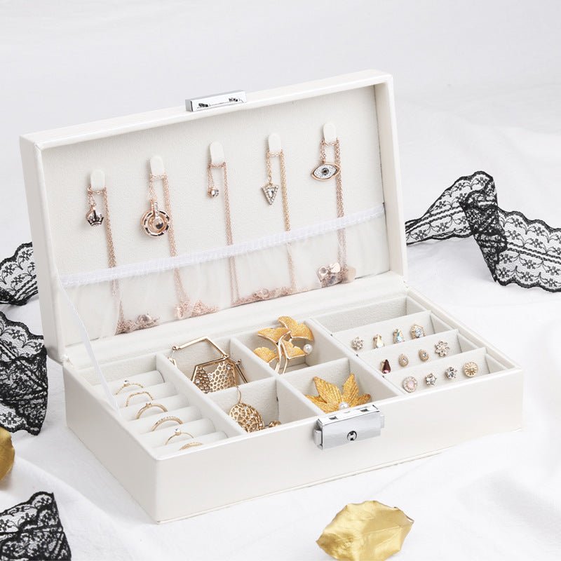 Boîte à bijoux blanche avec compartiments multiples et porte-boucles d'oreilles intégrés, design élégant et compact.