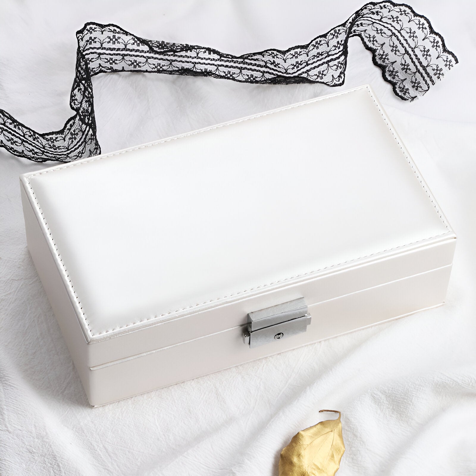Boîte à bijoux nomade blanche en cuir, fermoir métallique, rangement compact et élégant.