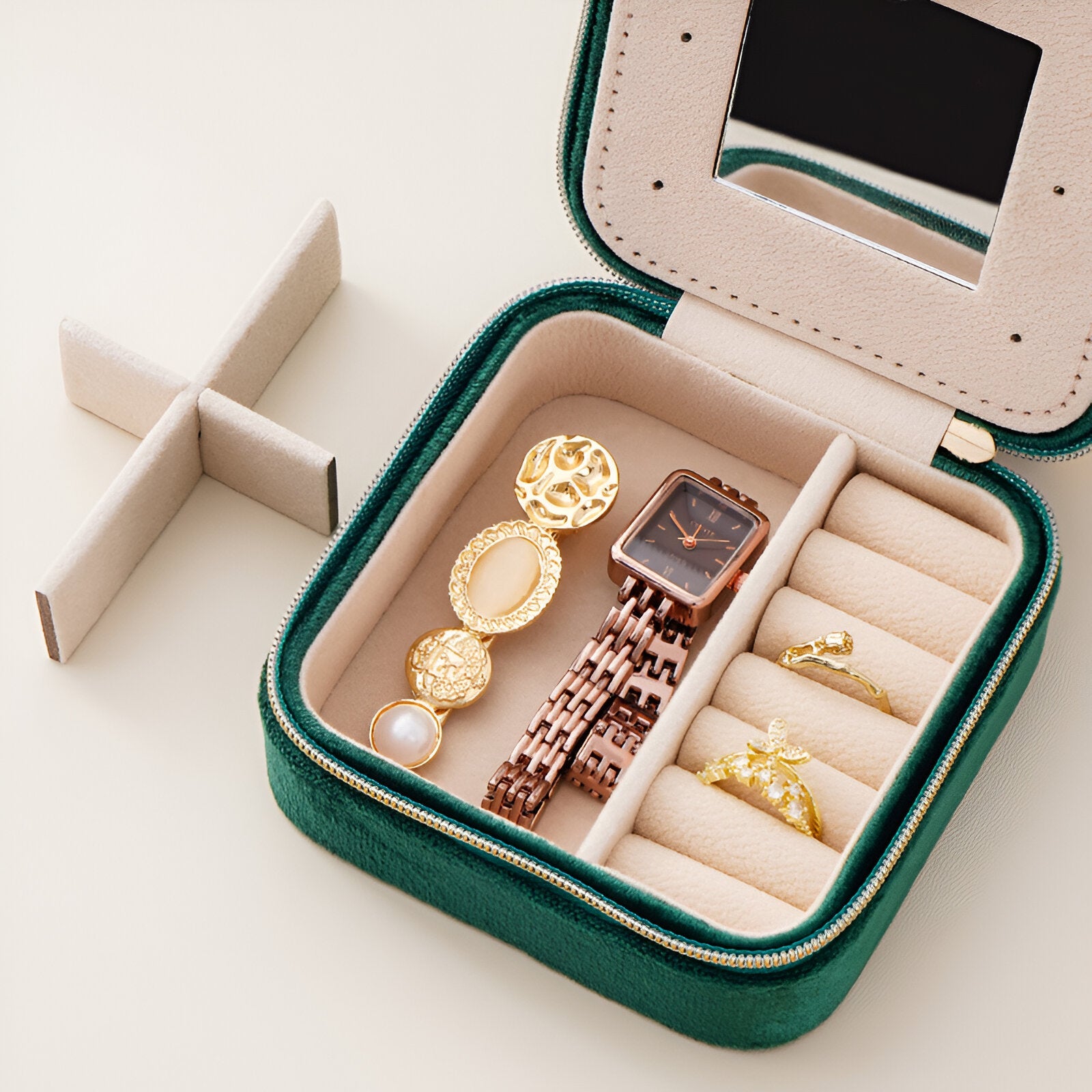 Boîte à bijoux en velours vert avec miroir, compartiments pour bagues et montre, bracelets et boucles d’oreilles dorés.