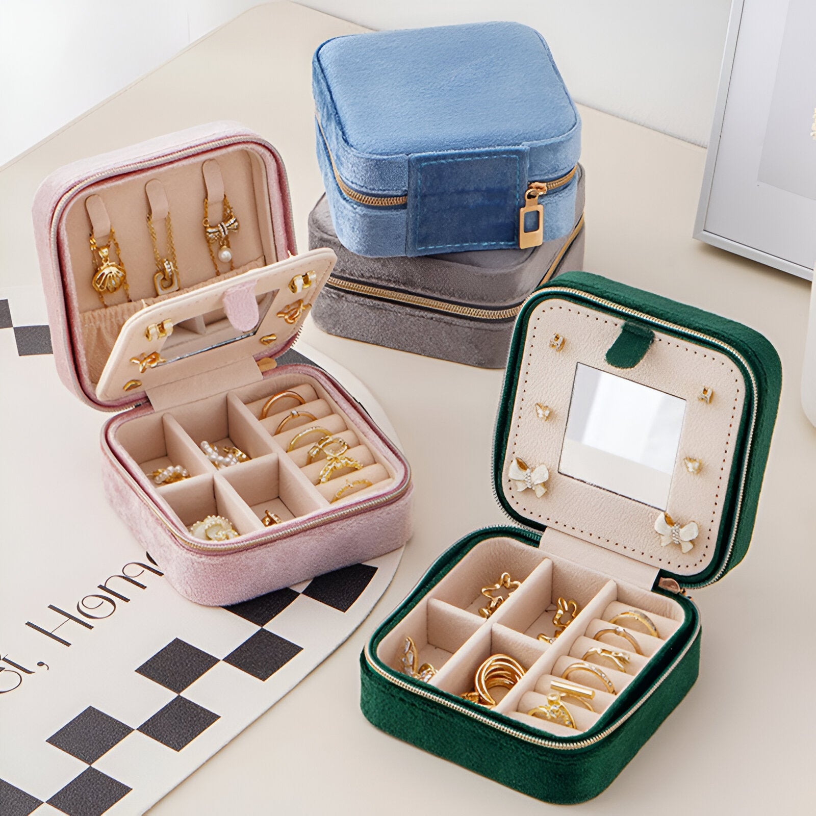 Boîte à bijoux nomade en velours rose avec compartiments et anneaux pour bagues, ouverture zip.