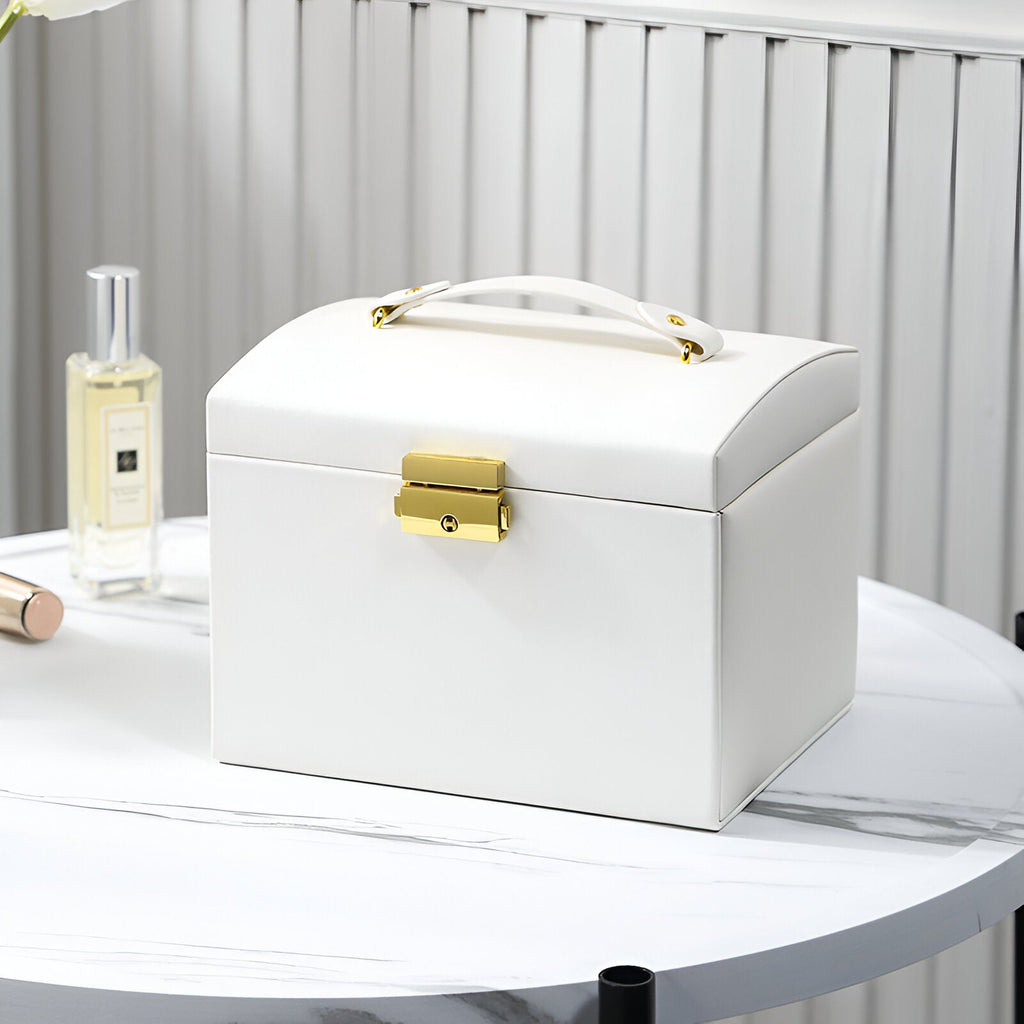 Boîte à bijoux blanche en cuir avec poignée et fermeture dorée, style élégant et compact.