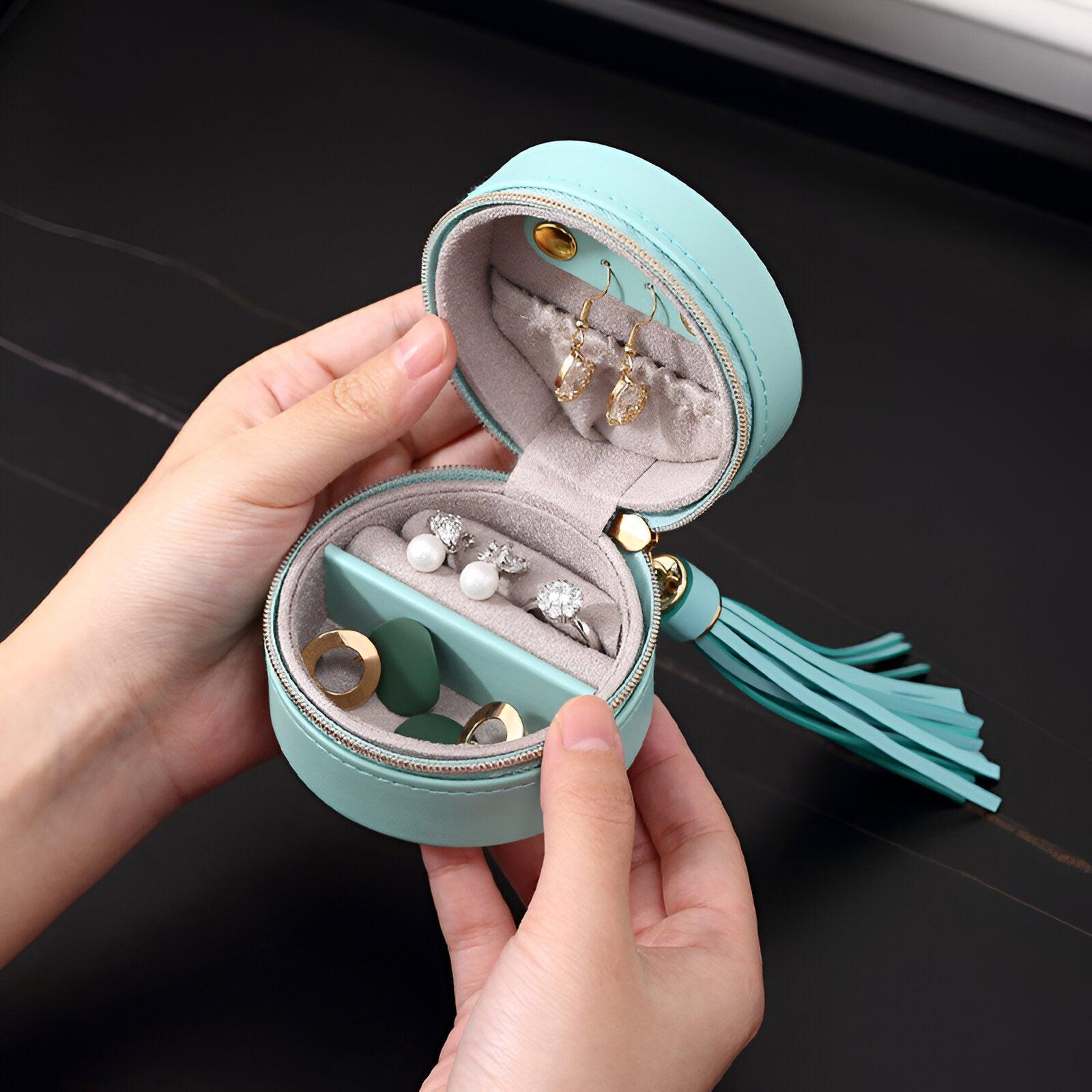 Boîte à bijoux mini format bleue avec pompon, intérieur velours crème et compartiments organisateurs.