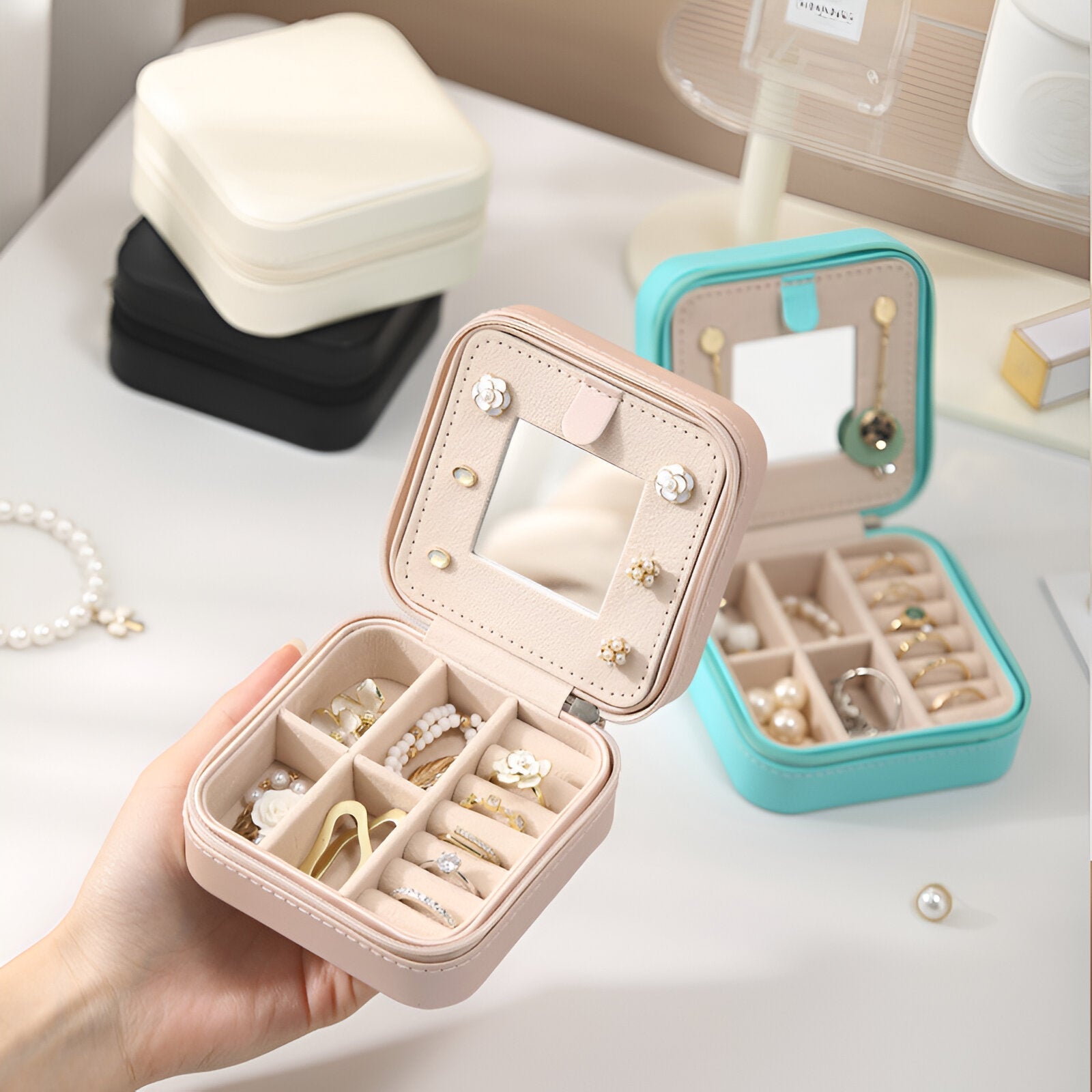Boîte à bijoux nomade rose avec miroir intégré et compartiments pour bagues et boucles d'oreilles.