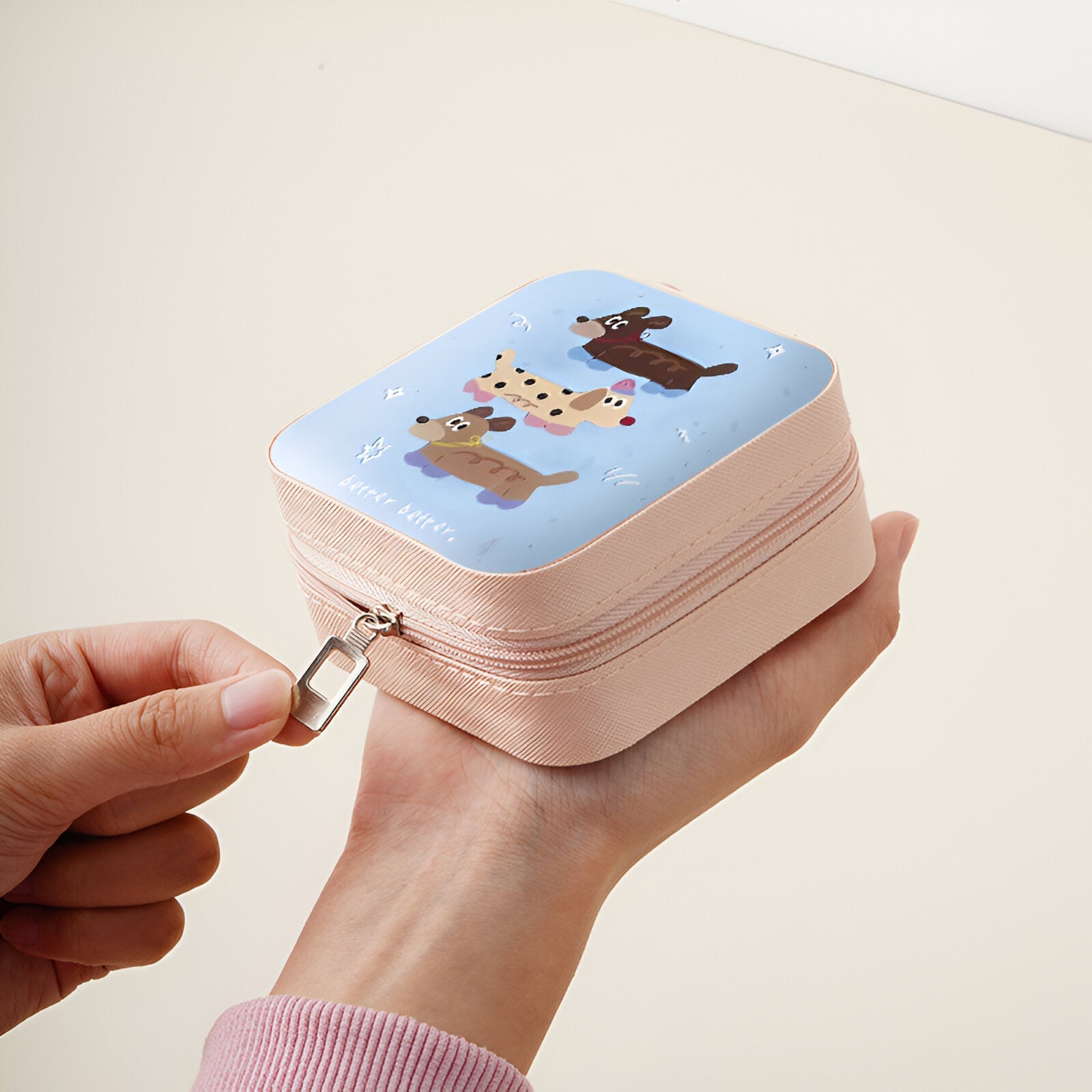 Boîte à bijoux nomade rose avec couvercle bleu décoré de personnages animaux enfantins.