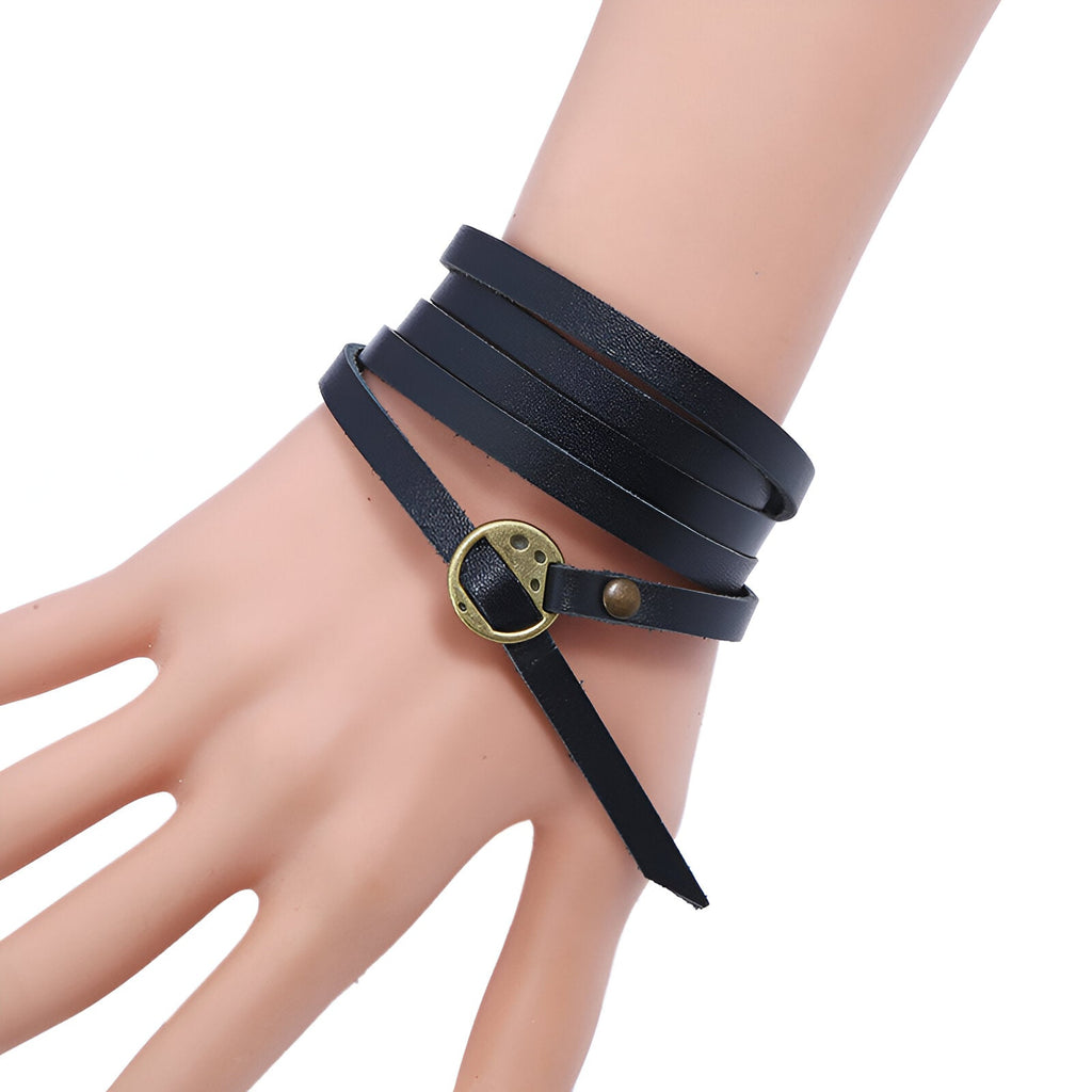 Bracelet en cuir noir vintage à enrouler avec boucle métallique dorée sur poignet homme.