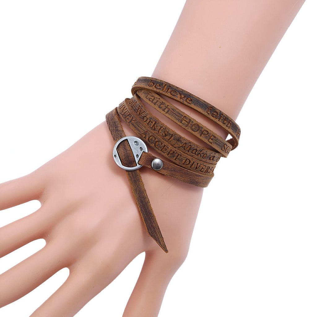 Bracelet à enrouler en cuir marron vieilli avec fermeture métallique argentée sur poignet.