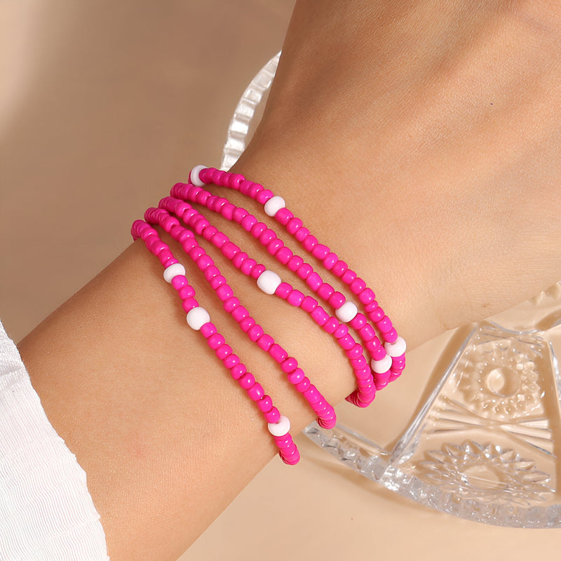 Bracelet à enrouler femme en perles élastiques fuchsia et blanches, style moderne et coloré.