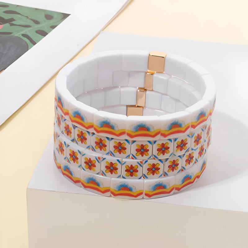 Bracelet large en acrylique blanc avec motifs floraux orange et cadre arc-en-ciel.