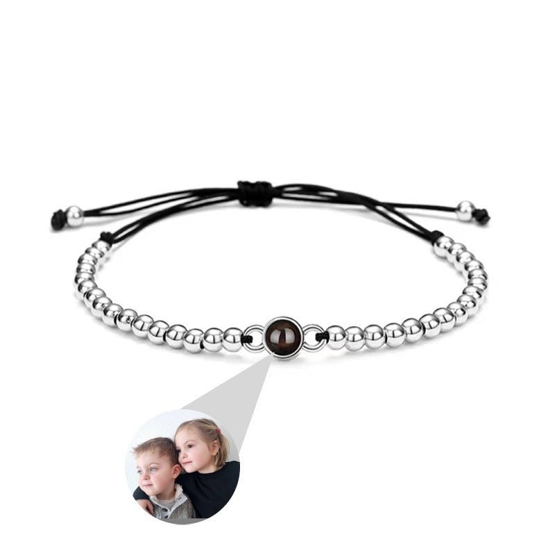 Bracelet à perles métalliques argentées avec perle centrale à projection photo sur cordon noir ajustable.