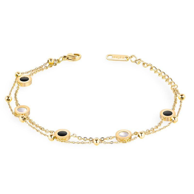 Bracelet ajustable doré en titane avec cinq motifs ronds noirs et blancs alternés sur chaîne fine.