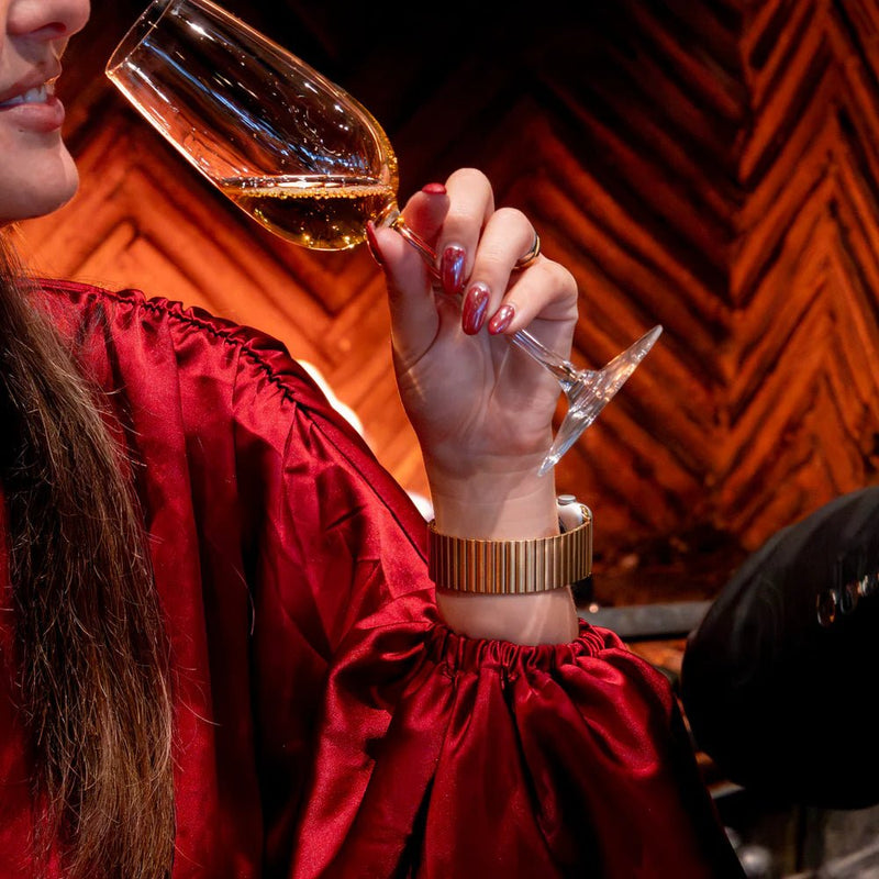 Bracelet Apple Watch à maillons élastiques en acier inoxydable doré, design extensible sans fermoir, porté au poignet.