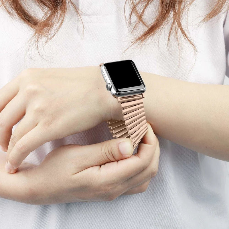 Bracelet extensible rose en acier inoxydable à maillons pour Apple Watch, sans fermoir, porté au poignet féminin.