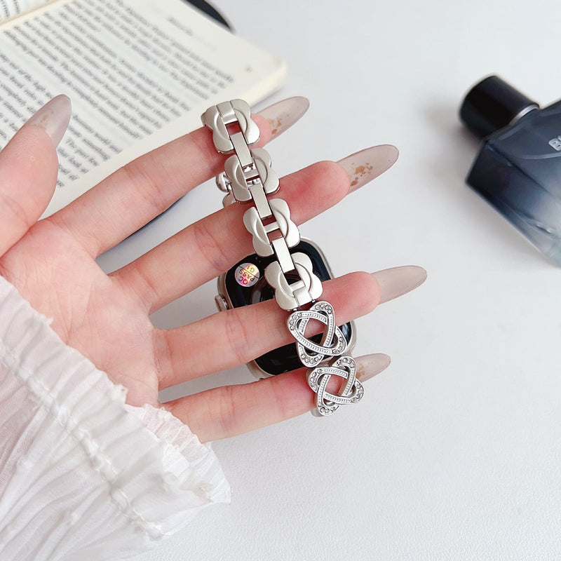 Pulseira para Apple Watch em metal prateado com malhas entrelaçadas, motivo de nó infinito cravejado de zircónias, fecho de encaixe ajustável, modelo Zergone