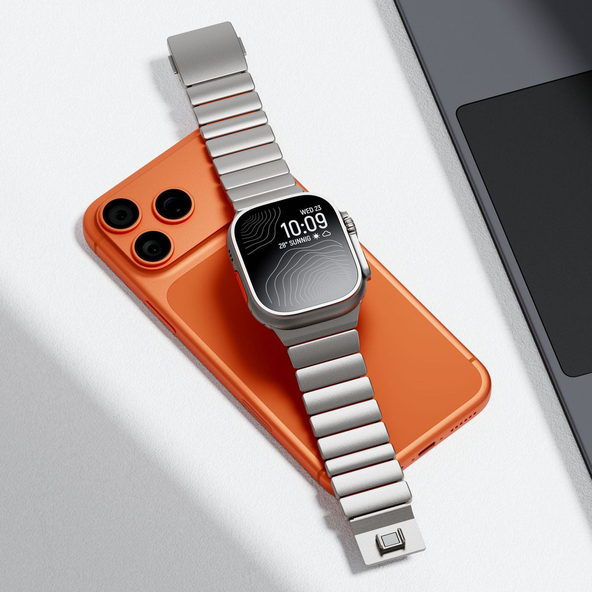 Bracelet Apple Watch en titane Grade 4 argenté, design rigide à maillons, fermoir carré intégré, posé sur un smartphone.
