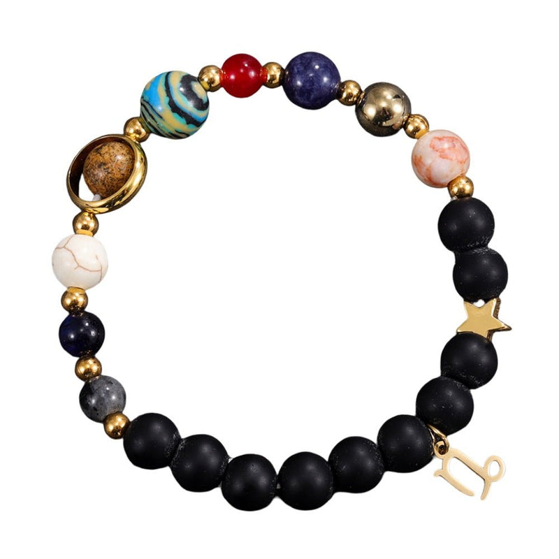 Bracelet élastique avec perles noires mates, pierres naturelles colorées et breloques dorées zodiacales sur fond blanc.