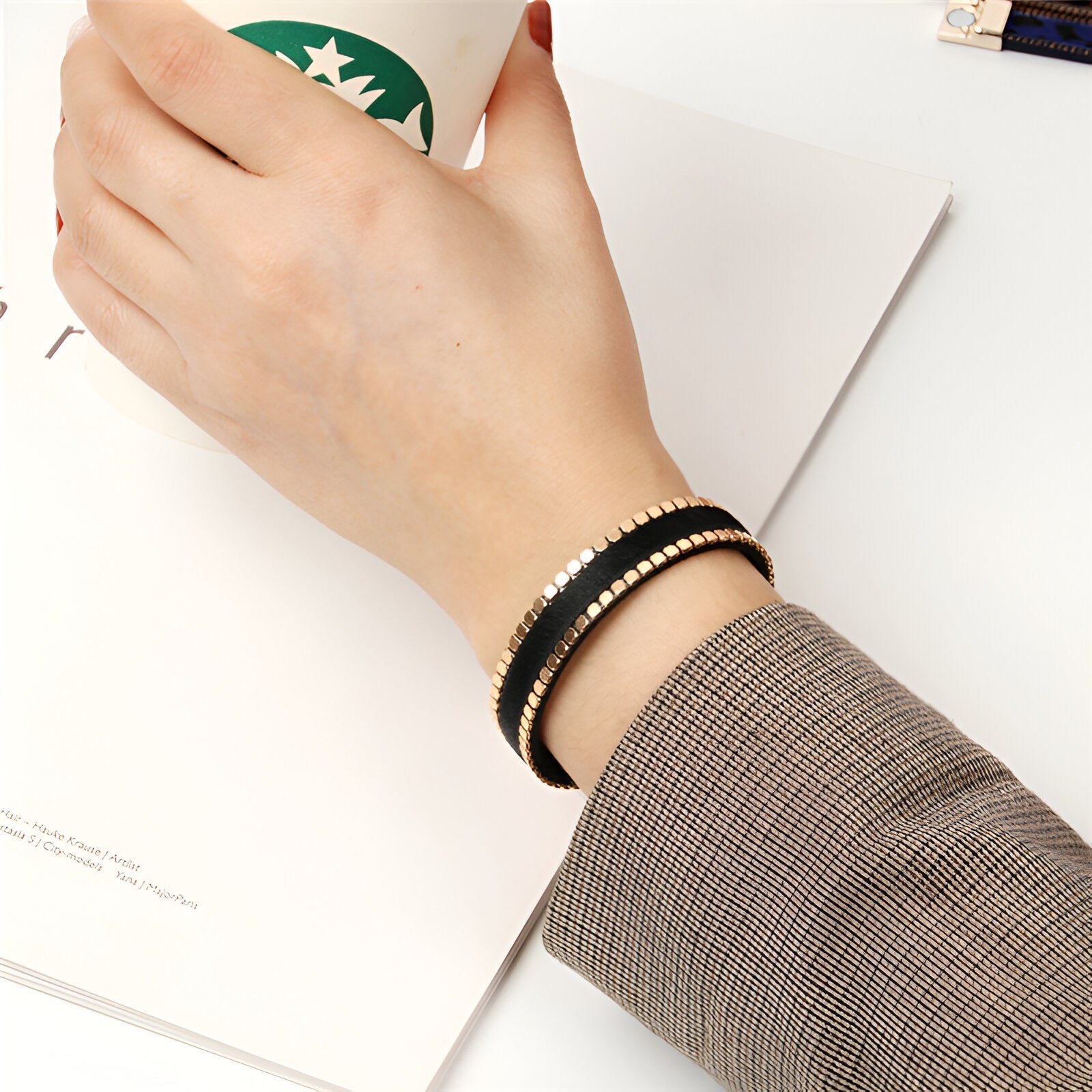 Bracelet fin noir avec détails léopard scintillants porté au poignet, style élégant féminin.