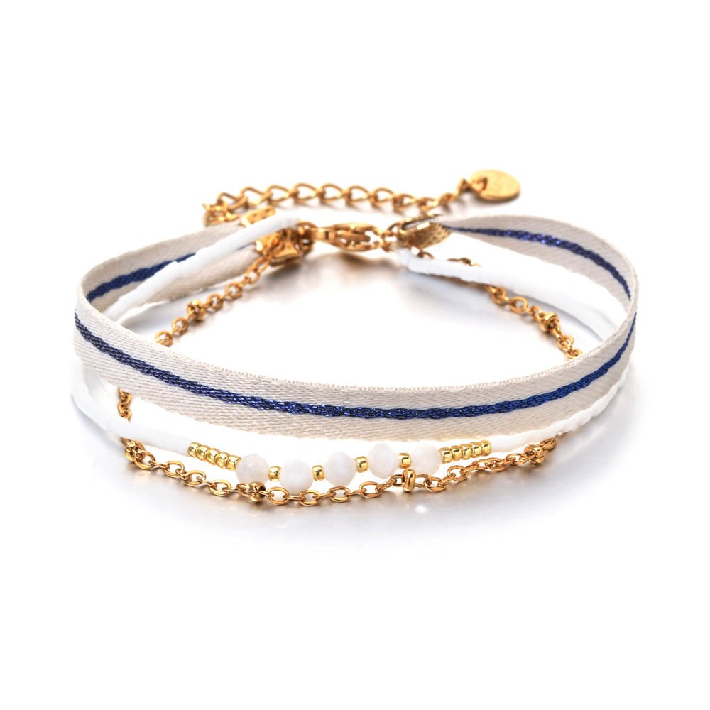 Bracelet bohème multirangs avec ruban rayé blanc et bleu, perles blanches fantaisie, chaîne dorée fine, fermoir mousqueton.
