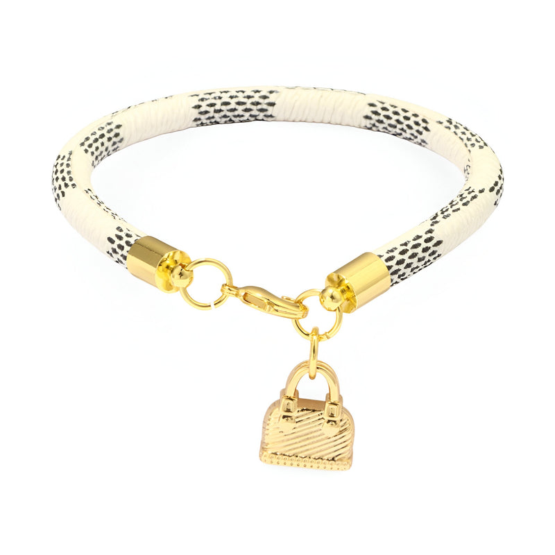 Bracelet en microfibre blanc à motifs noirs avec breloque sac à main dorée élégante.