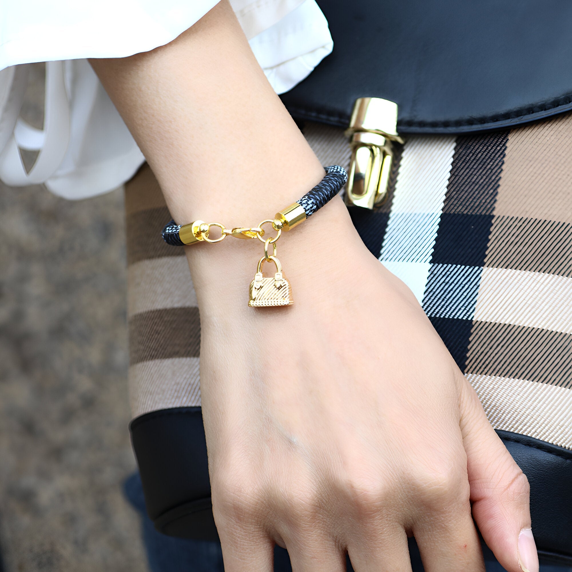 Bracelet femme en microfibre noir avec breloque sac à main dorée et chaîne délicate.