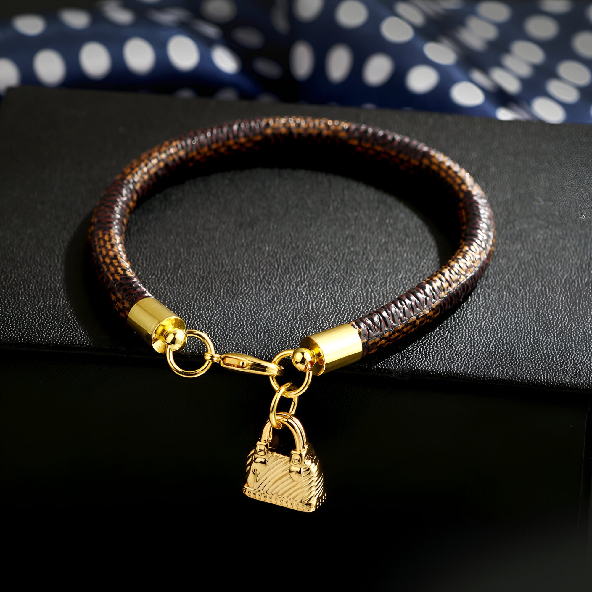 Bracelet charm sac à main en microfibre café avec breloque dorée en forme de sac à main.