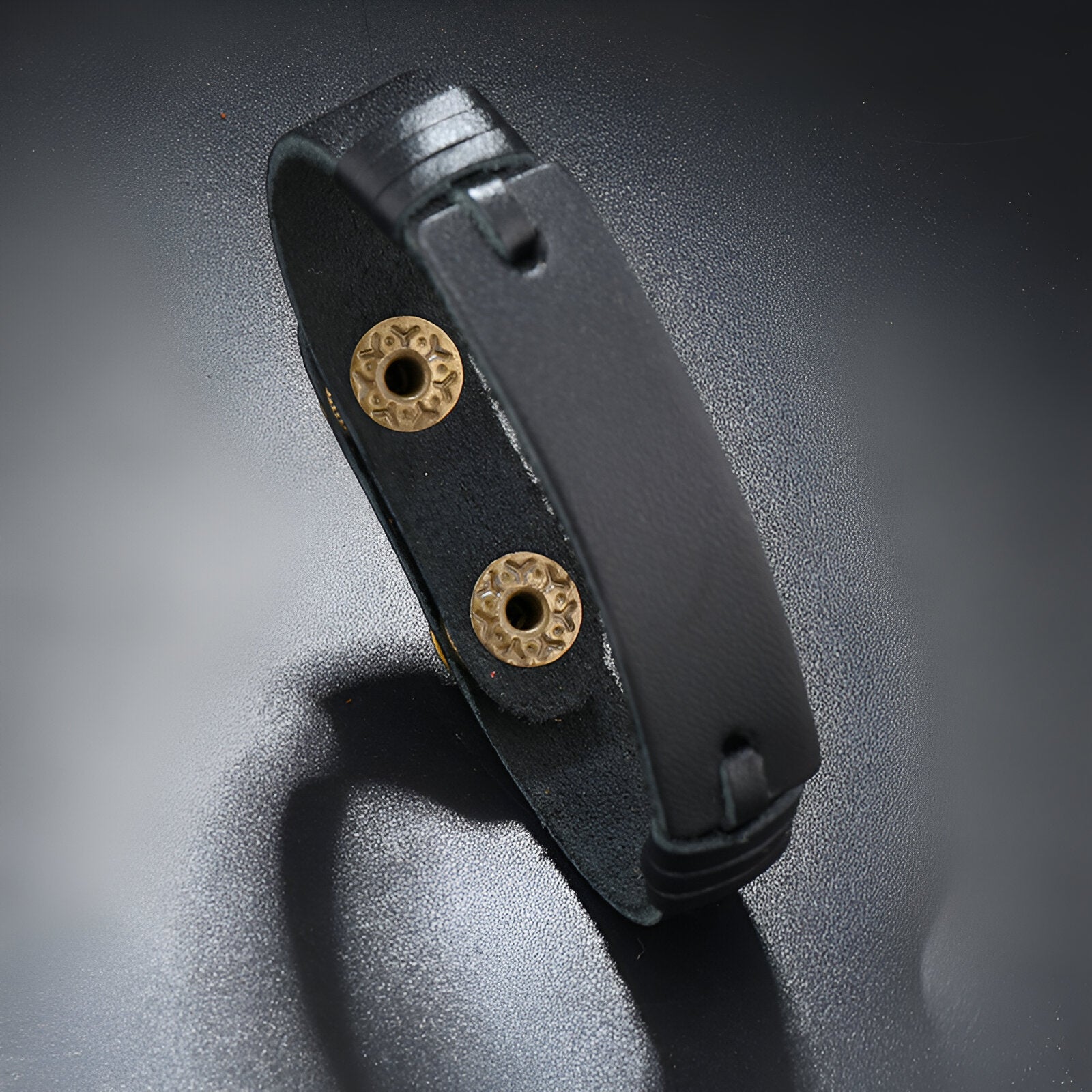 Bracelet en cuir noir effet vintage avec fermoirs circulaires en métal doré élégant.
