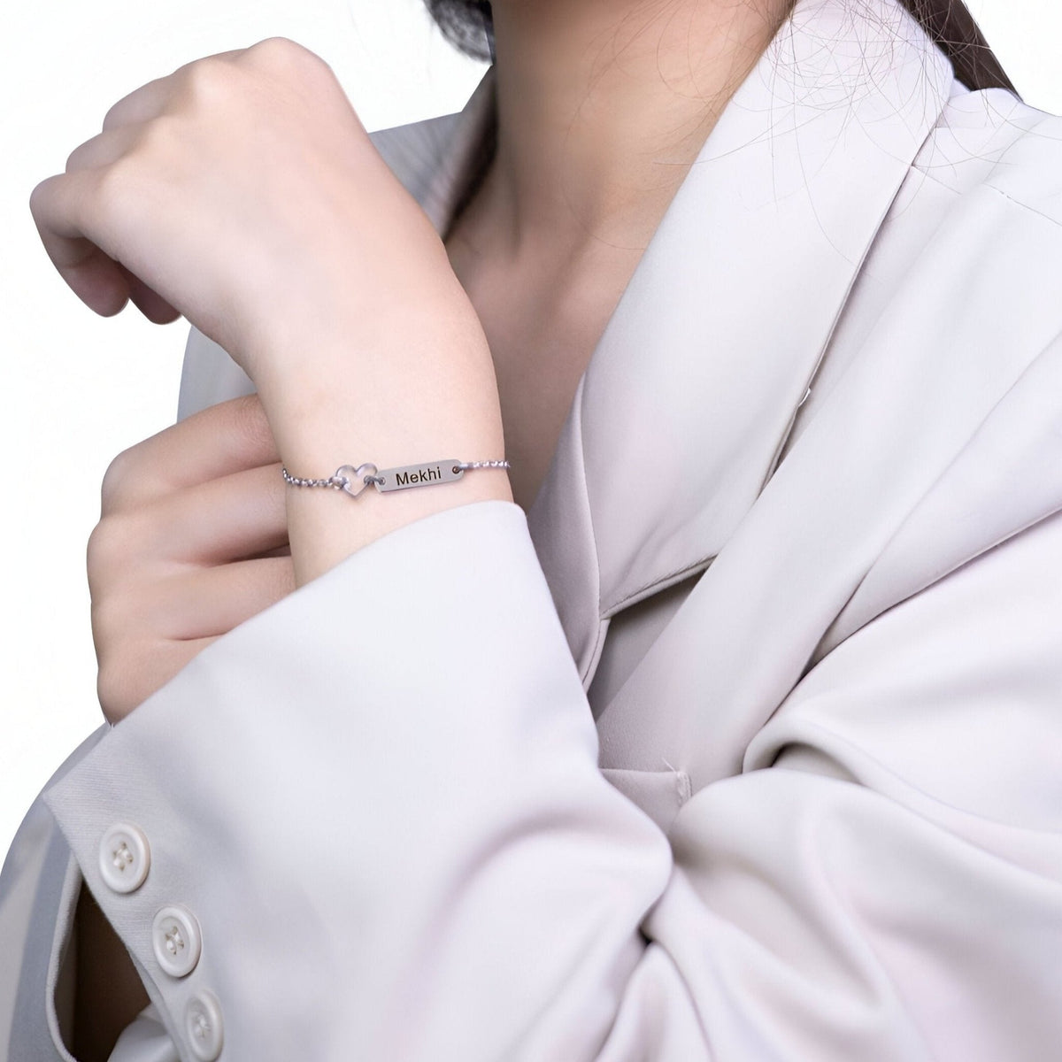 Bracelet argenté en acier inoxydable avec pendentif cœur délicat, porté sur poignet féminin.