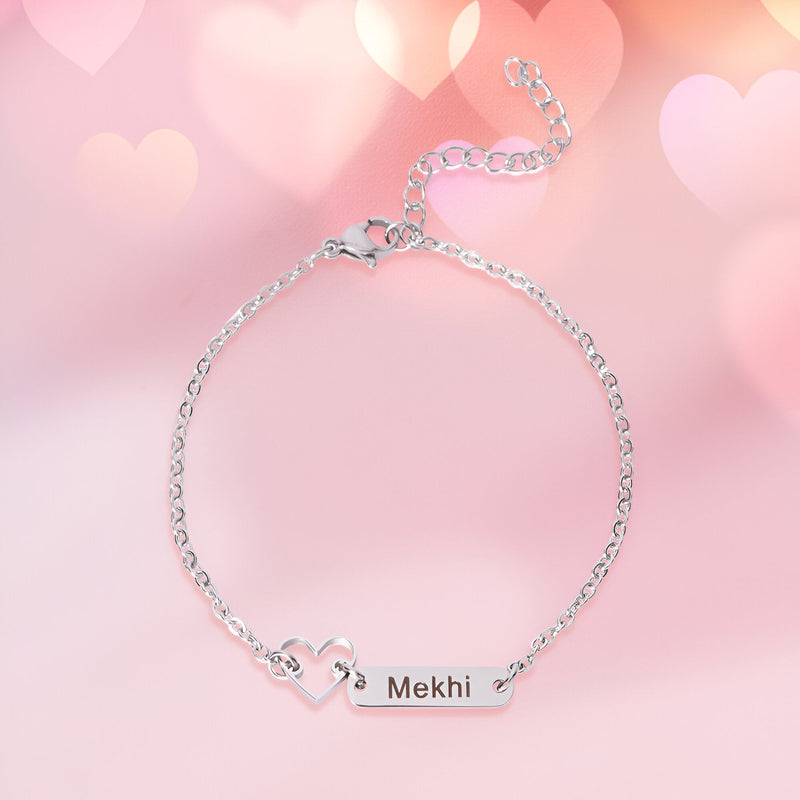 Bracelet fin en acier inoxydable argenté avec pendentif plaque gravée et cœur ajouré.