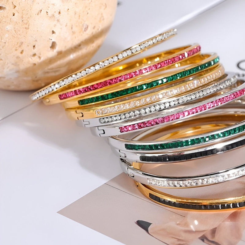 Bracelets fins empilés en acier inoxydable plaqué or avec pierres colorées et cristaux scintillants.