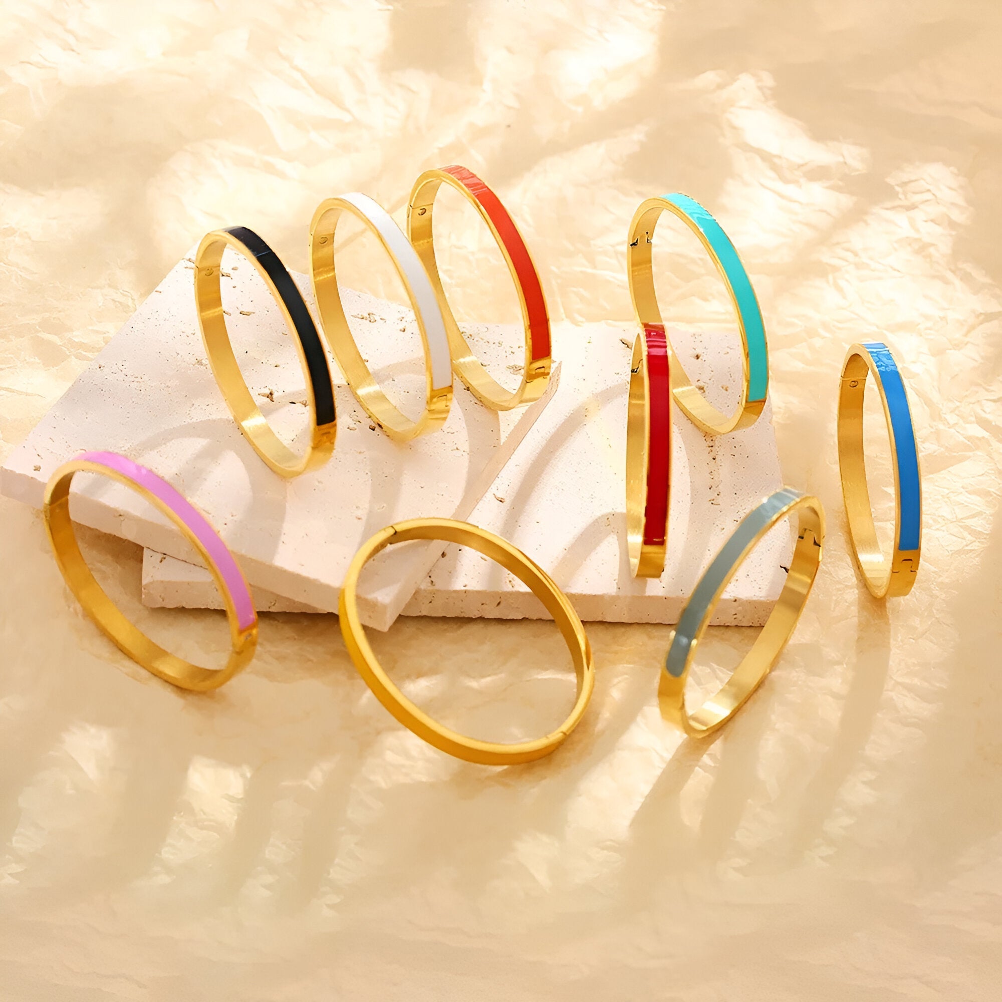 Bracelets joncs émaillés colorés en titane plaqué or, couleurs variées dont rose, noir, bleu, rouge et turquoise.