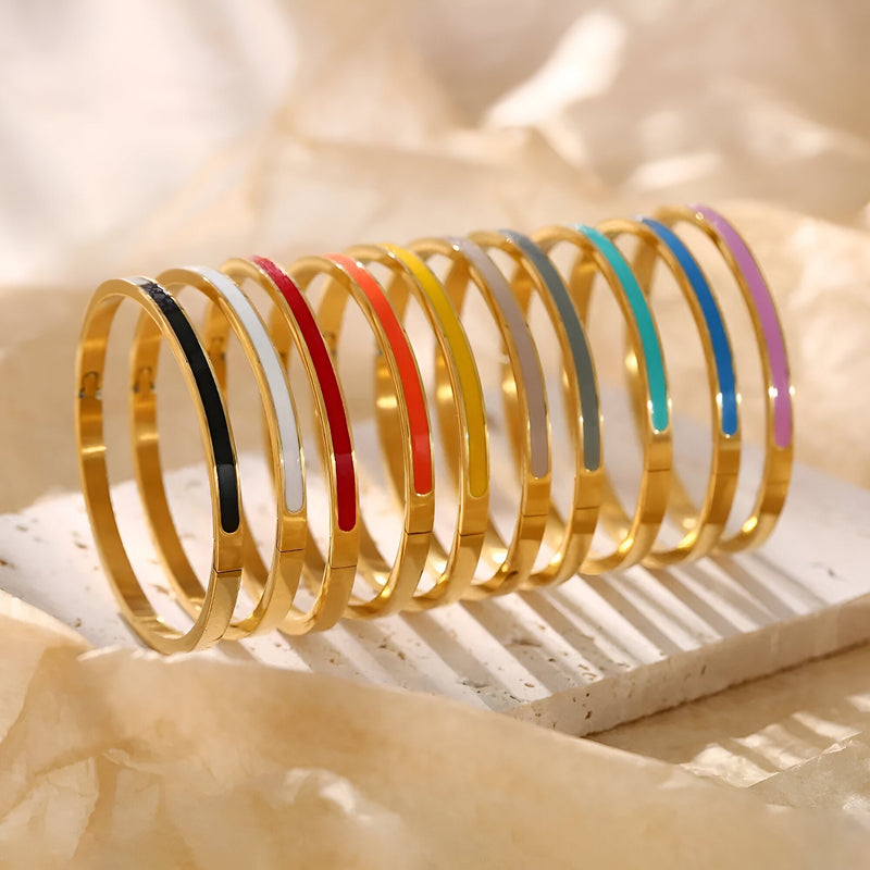Bracelet jonc plaqué or en titane avec émail coloré, couleurs variées alignées sur support blanc.