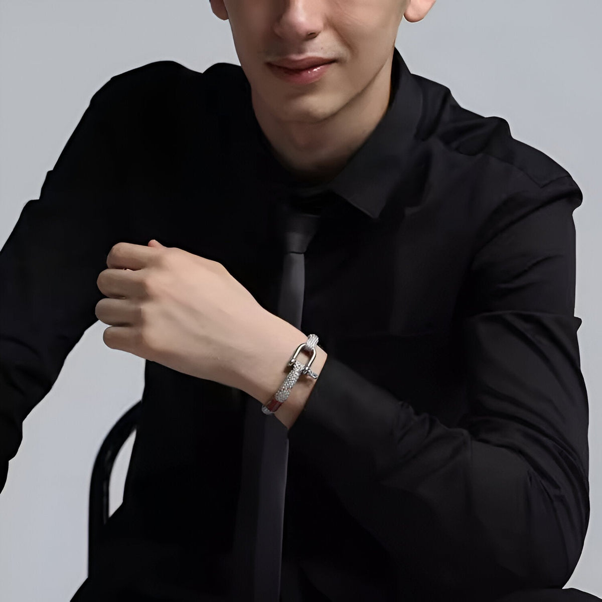 Bracelet cordon blanc avec mousqueton en acier inoxydable porté par homme en chemise noire.