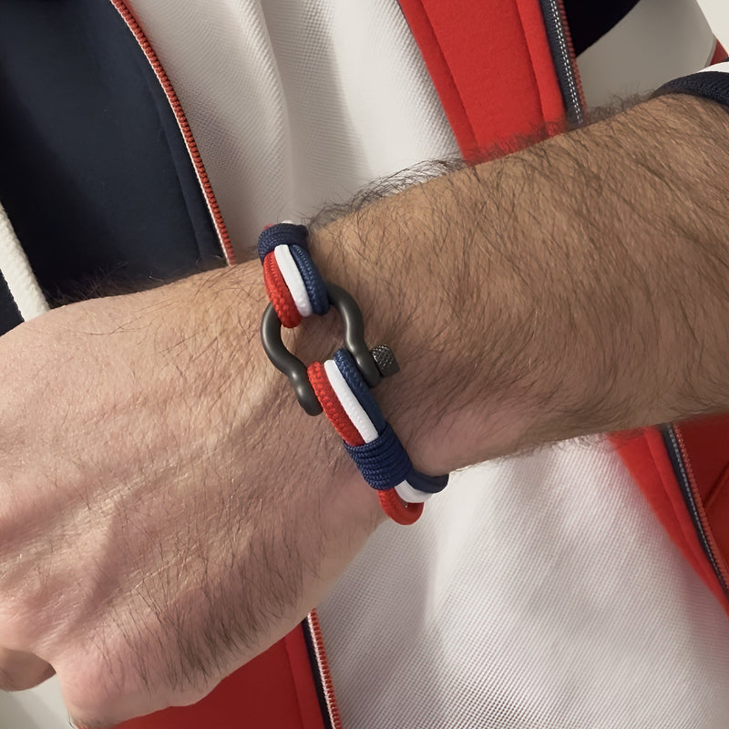 Bracelet tricolore bleu blanc rouge en cordon avec mousqueton en acier inoxydable sur poignet masculin.