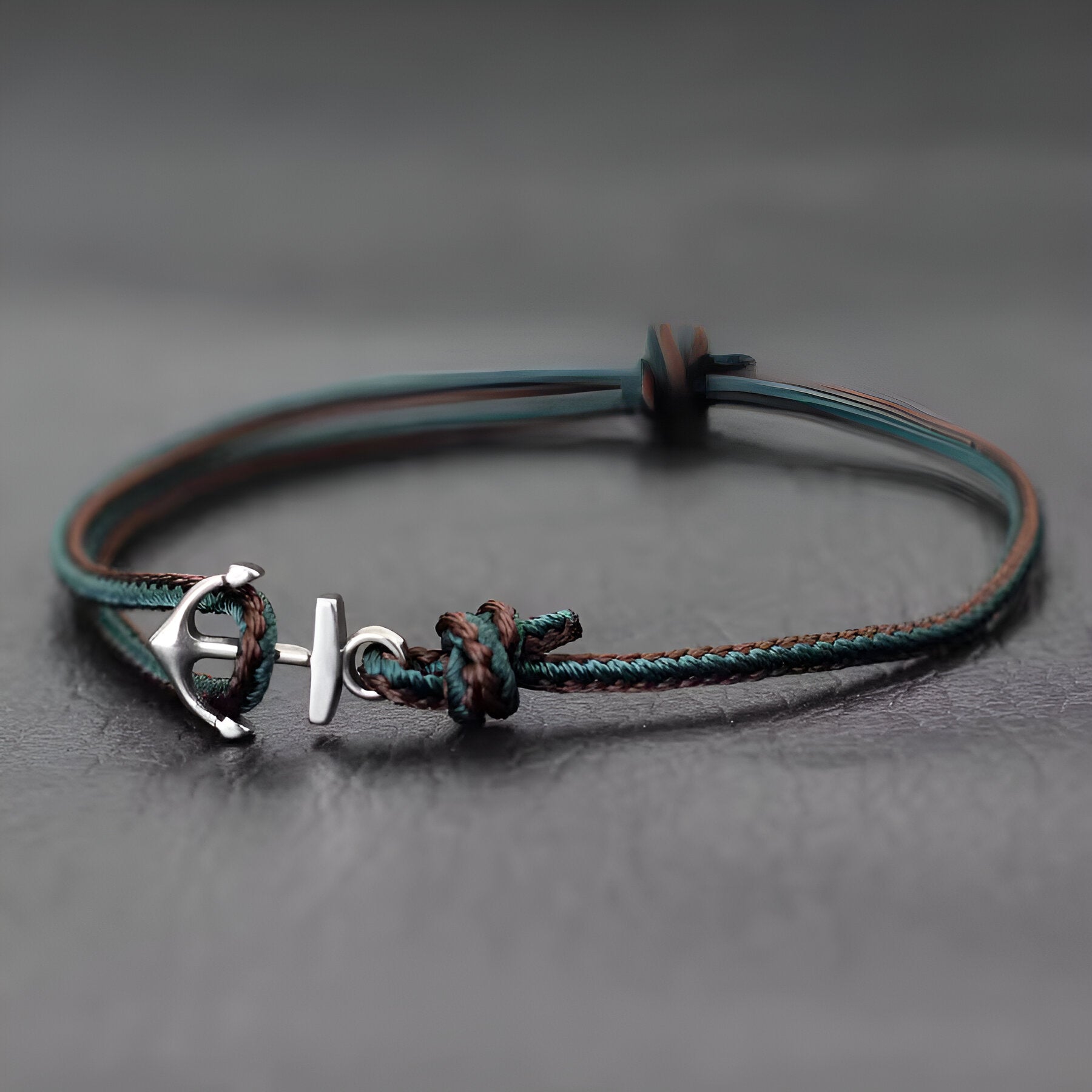 Bracelet cordon vert foncé avec ancre marine en métal argenté et nœud coulissant.