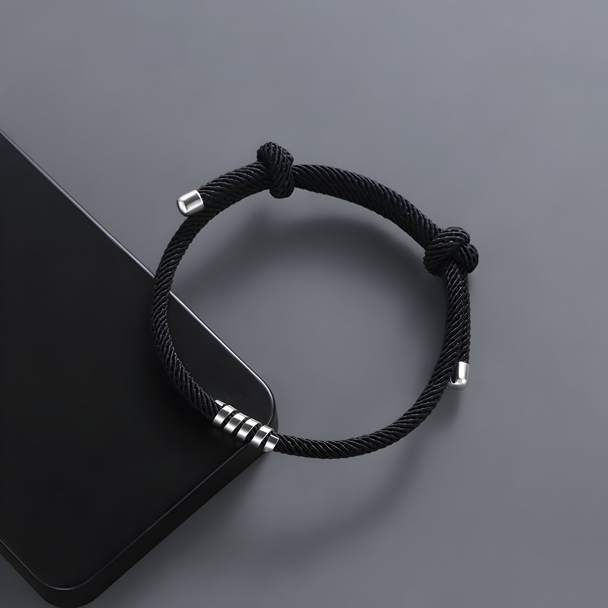 Bracelet cordon noir en titane avec design minimaliste et détails métalliques pour homme.