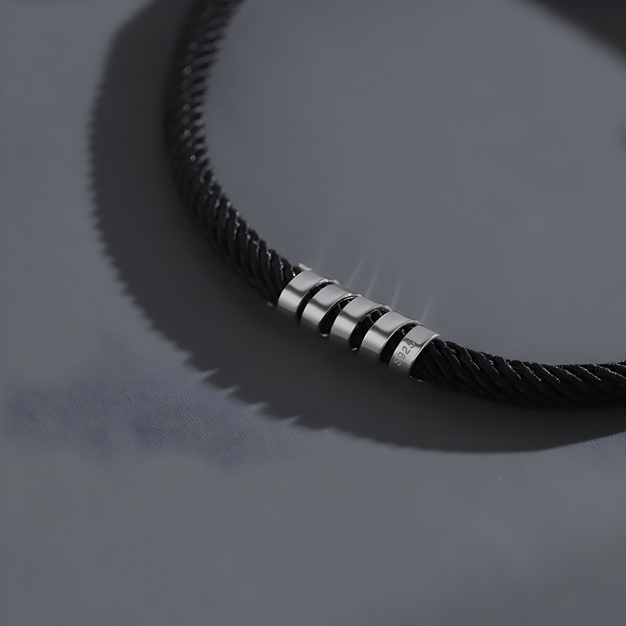 Bracelet cordon noir minimaliste avec anneaux en titane brossé pour homme.