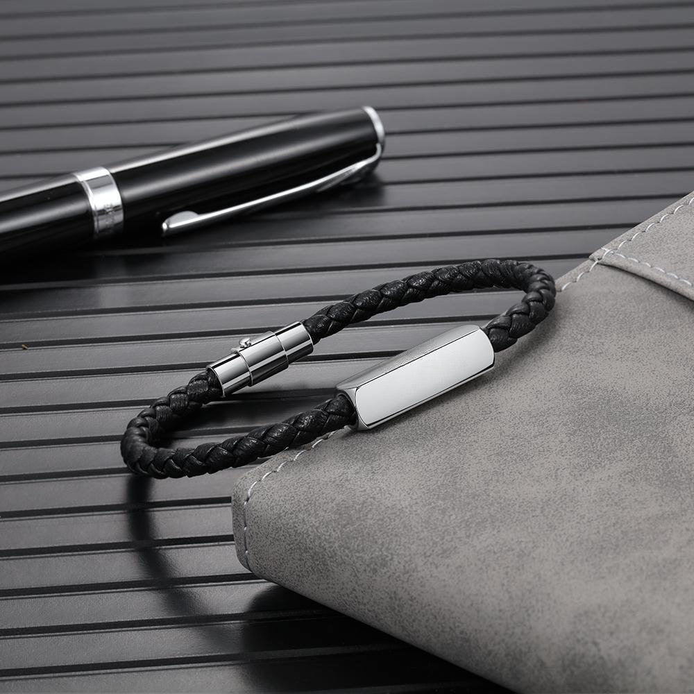 Bracelet cordon noir en cuir tressé avec plaque argentée et fermoir métallique élégant.