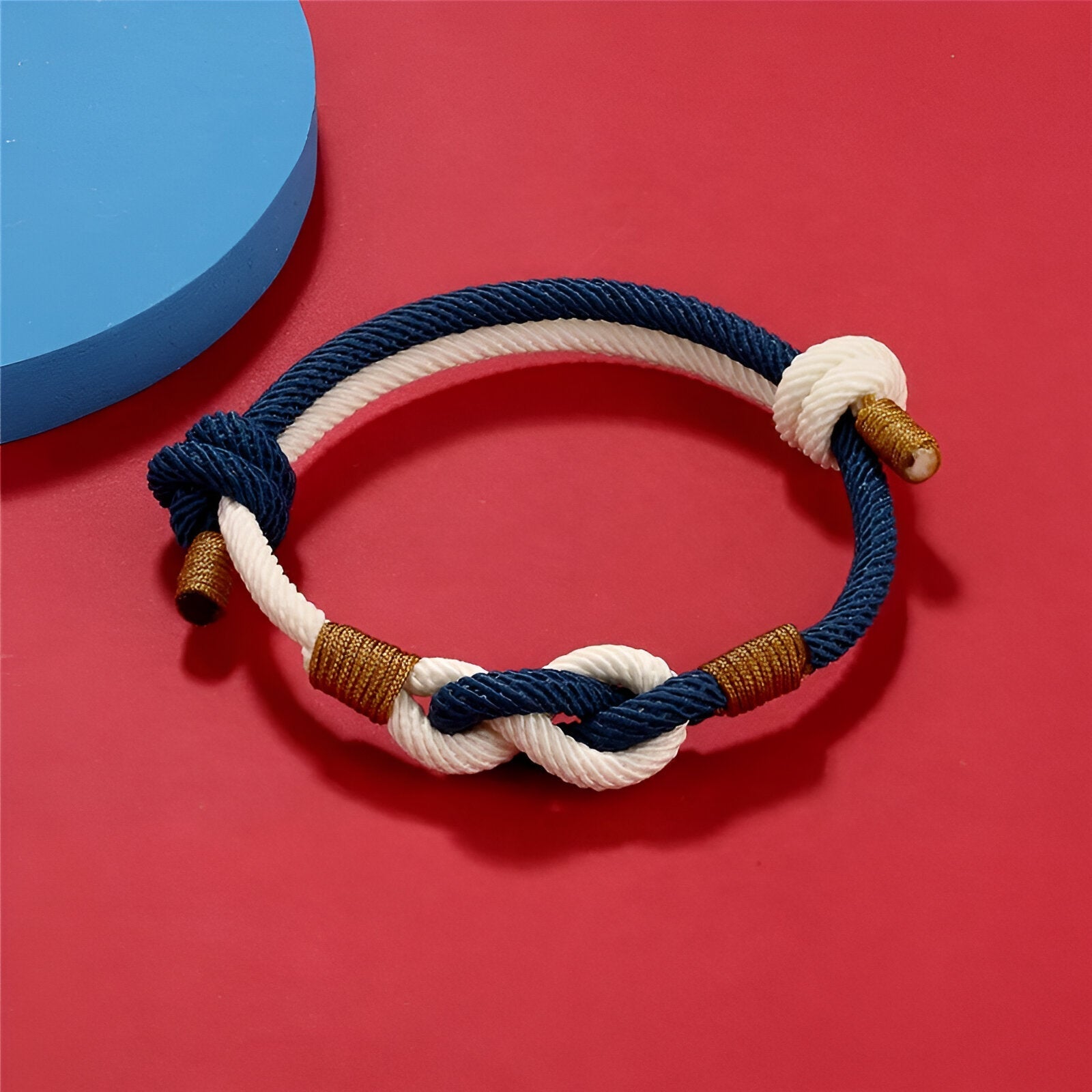 Bracelet cordon bicolore bleu et blanc à nœud central et détails marron.
