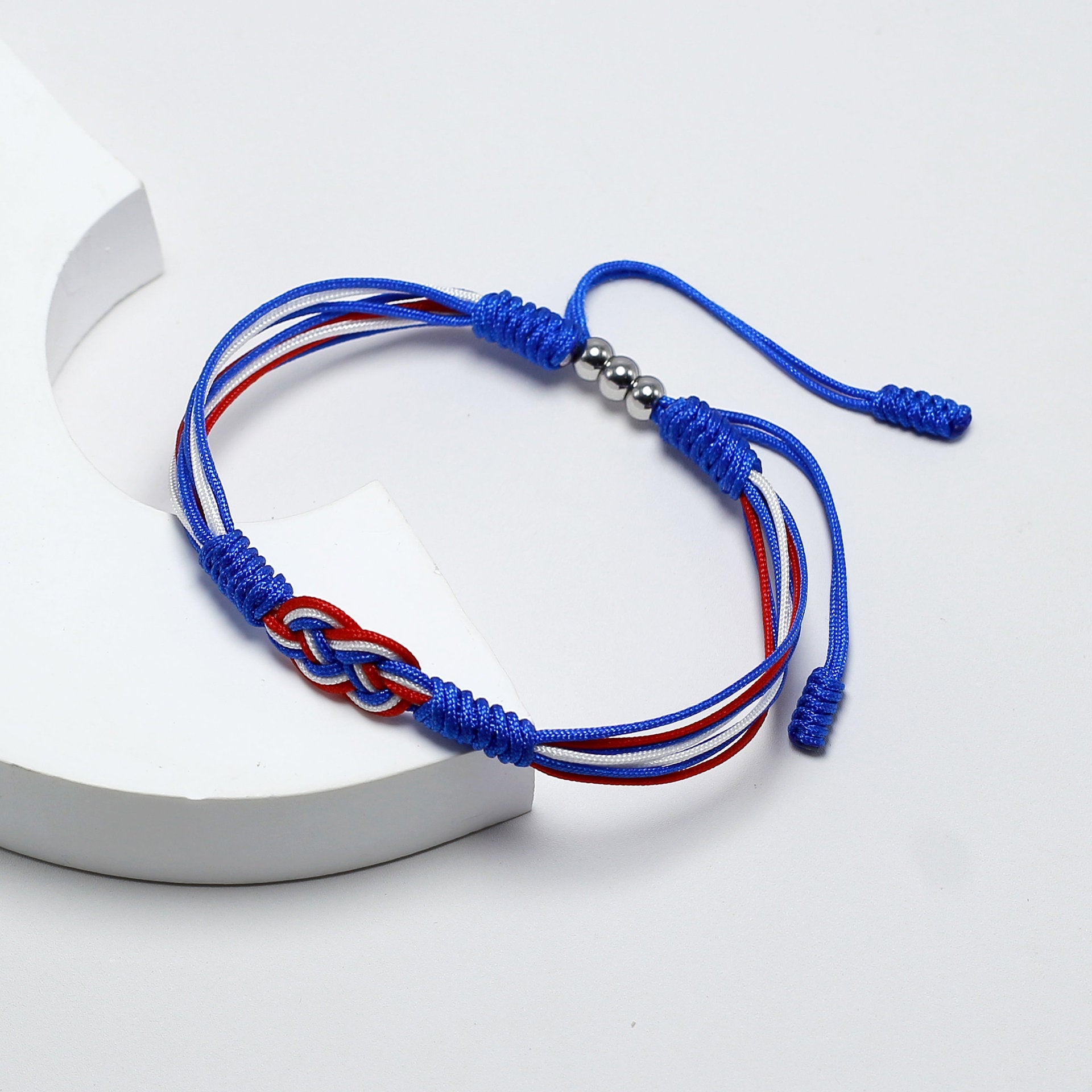 Bracelet cordon bleu et rouge avec noeud plat couleur drapeau France et fermoir métal argenté.